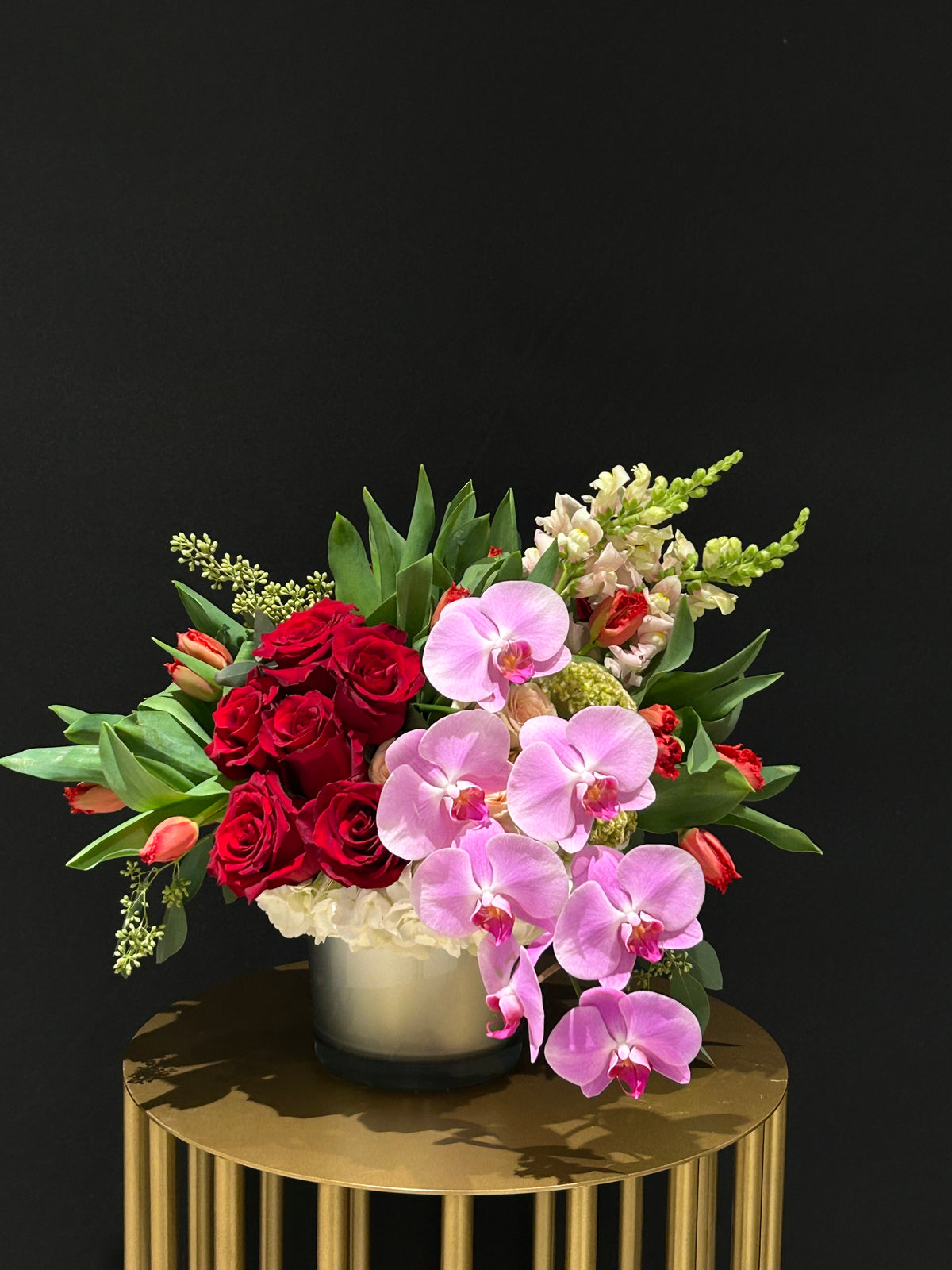 "Express love with Love Smile Arrangement – a masterpiece of red roses, tulips, orchids, and snaps. Perfect for V-Day, anniversaries, birthdays. Local GTA delivery, front