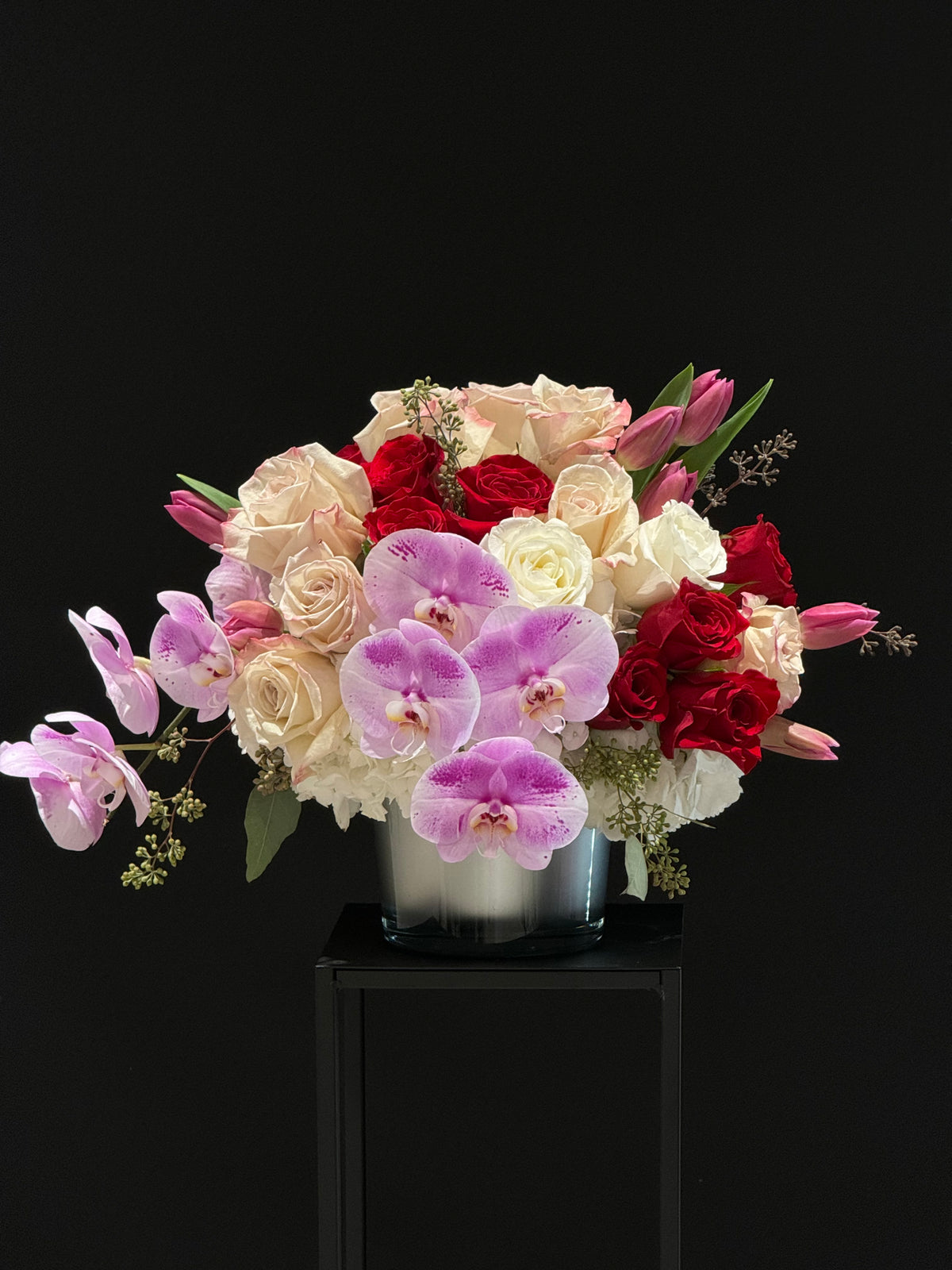 "Love Bloom Arrangement: Red, pink, and white roses, tulips, hydrangeas, and purple orchids in a luxurious display. Perfect for special occasions. Order now for local/GTA delivery!"