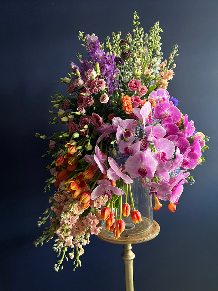 "Vivid Harmony Floral Arrangement: A burst of nature's colors featuring delphiniums, stocks, anemones, lisianthus, tulips, orchids, and mini calla lilies. Perfect for congratulating a new home, celebrating anniversaries, or sending birthday wishes. Expertly crafted by Yonge Florist for local and GTA flower delivery." back photo